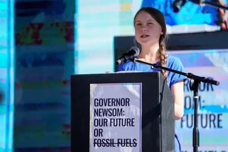 Photo of Greta Thunberg wearing blue shirt speaking at podium during her US campaign