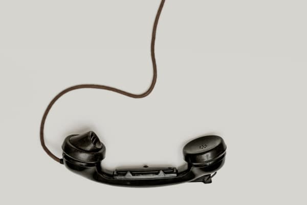 Photo of black telephone dangling from its cord