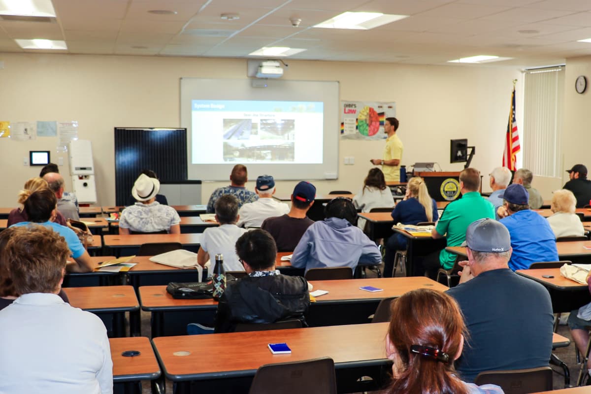 Photo of seminar attendees listening to solar power presentation and taking notes