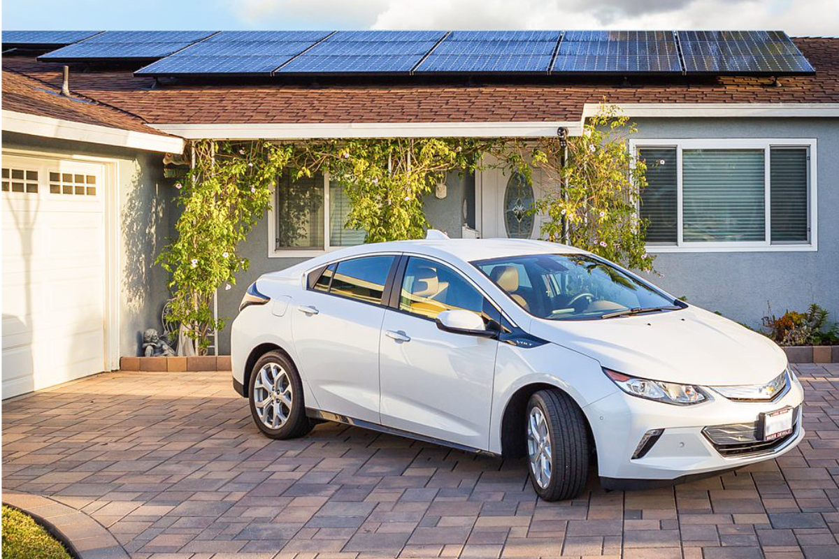 Photo of electric vehicle parked in driveway of solar powered home