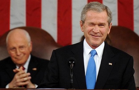 Photo of President George Bush winking with the American flag in the background