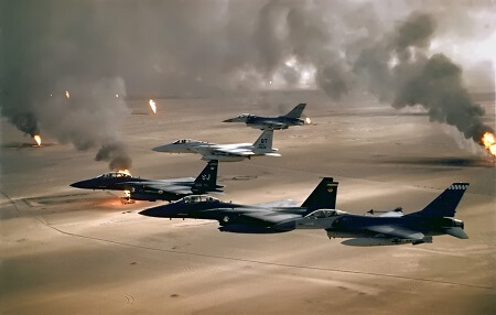 Image of five fighter jets flying in formation over burning field