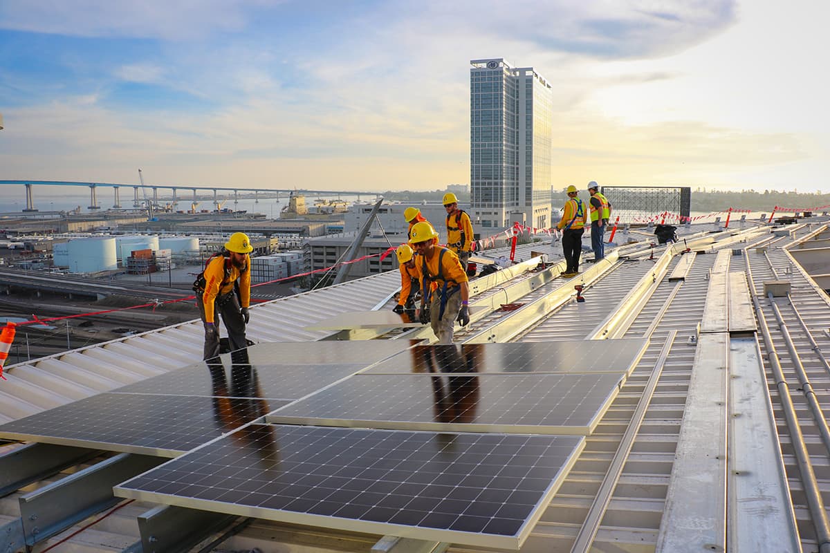 Electricians installing solar power system at Petco Park with Coronado Bridge in background