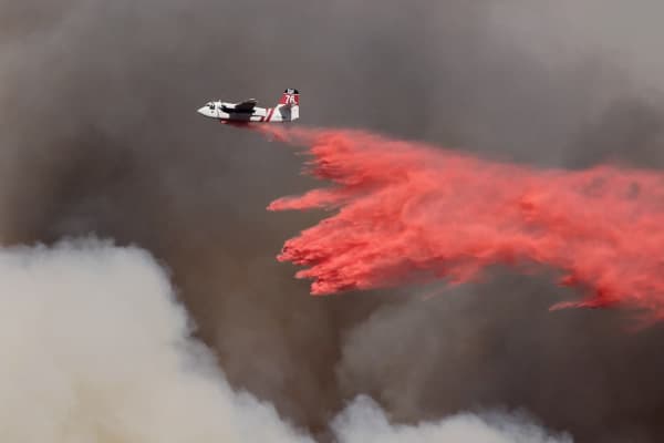 Photo of low flying airplane in smokey sky helping extinguish fire