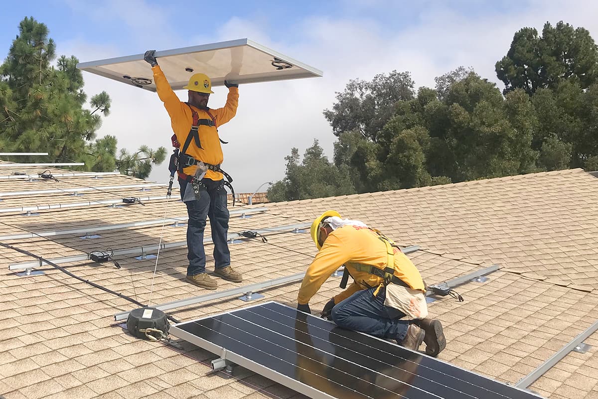 Two Sullivan Solar Power electricians installing solar panel on rooftop of Good Samaritan Episcopal Church