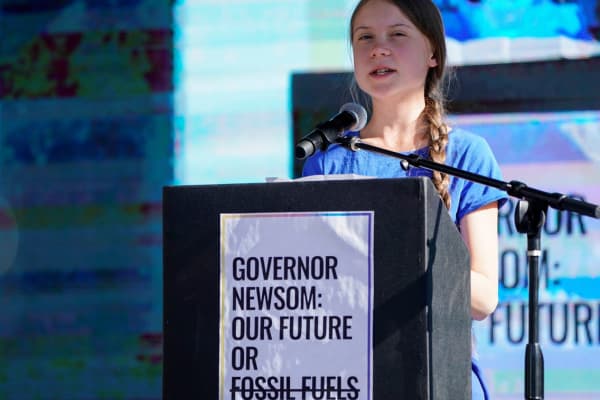 Photo of Greta Thunberg wearing blue shirt speaking at podium during her US campaign