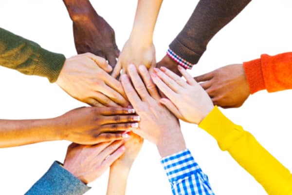 Overhead photo of ten hands with different skin tones and colorful clothing coming together to form a circle