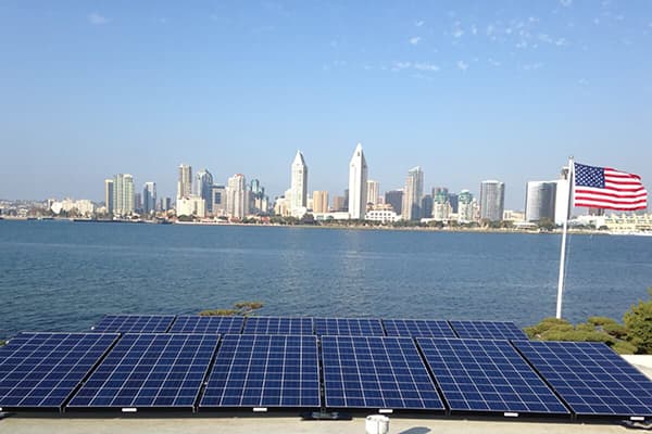 Scenic photo of solar array and American flag in foreground with Downtown San Diego skyline in background